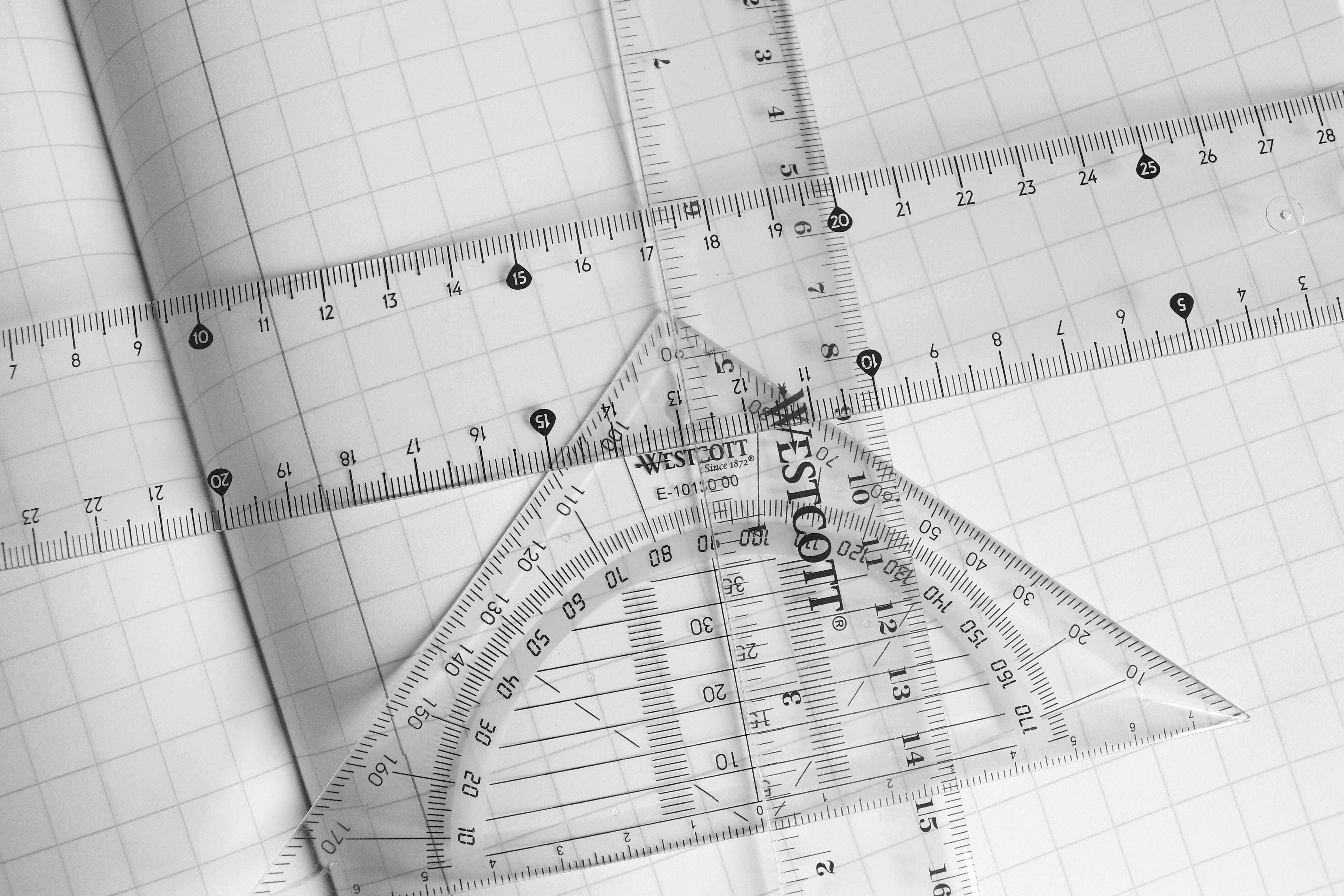 Professional geometry tools including rulers, protractors, and set squares arranged on graph paper for mathematical precision and measurement